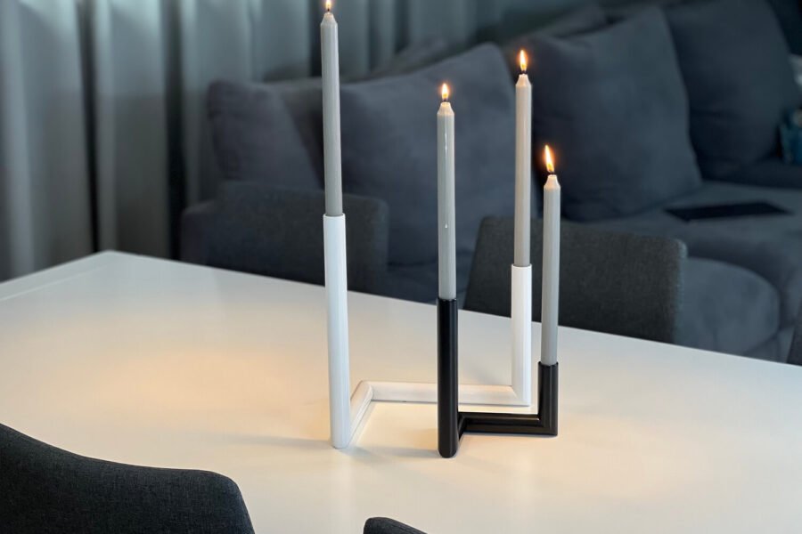 Komplet dwóch świeczników stołowych Aves i płonące świece. Producent Sigma Design.