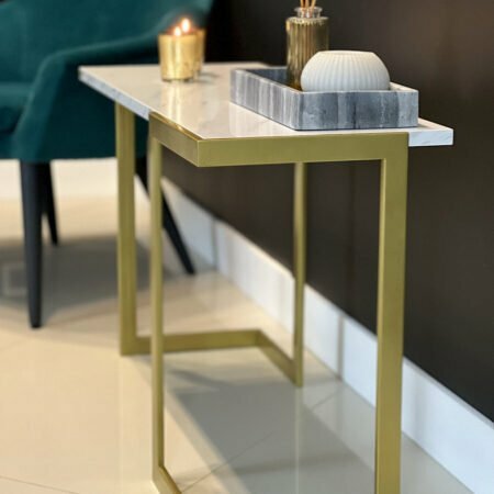 Maly stolik pomocniczy ze złotymi nogami i białym blatem.