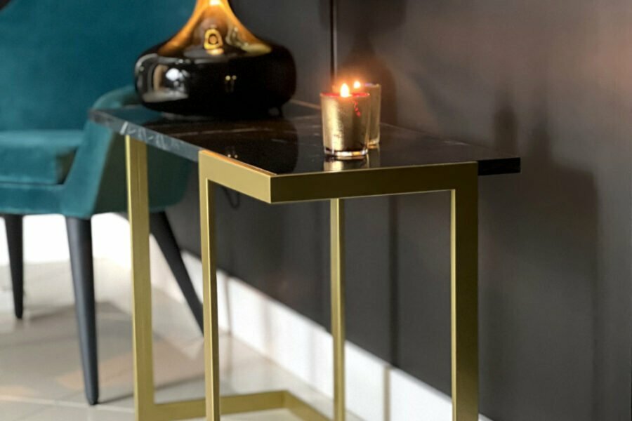 Dekoracyjny stolik pomocniczy z czarnym marmurem i złotymi nogami.