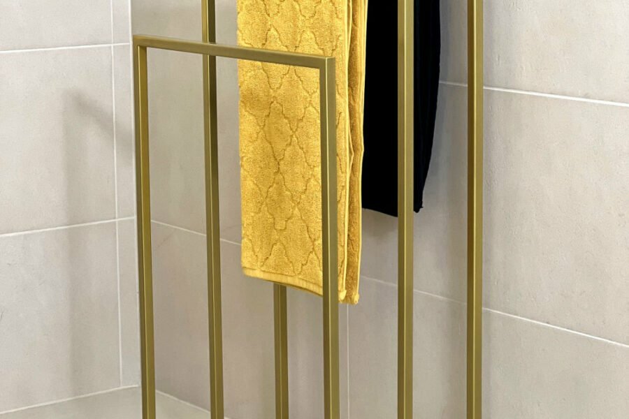 Wieszak na ręczniki w łazience w kolorze złotym.
