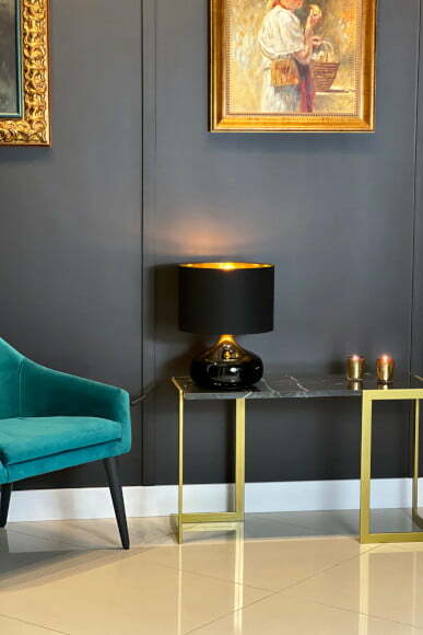 Jak stworzyć przytulne wnętrze. Dekoracyjny stolik pomocniczy w kolorze zlotym i z czarną lampą.